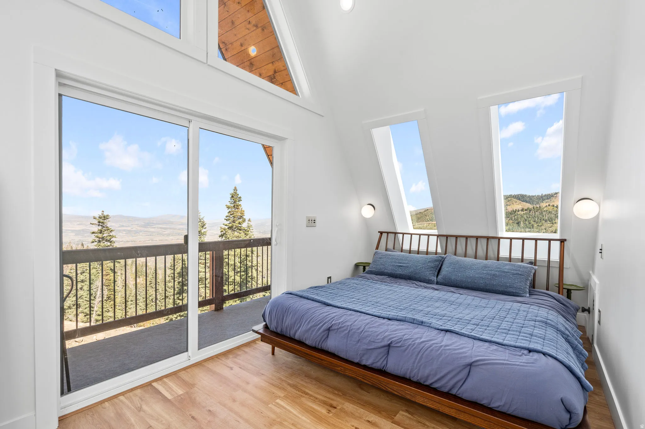 Bedroom featuring light wood-style flooring, a mountain view, access to exterior, and a high ceiling