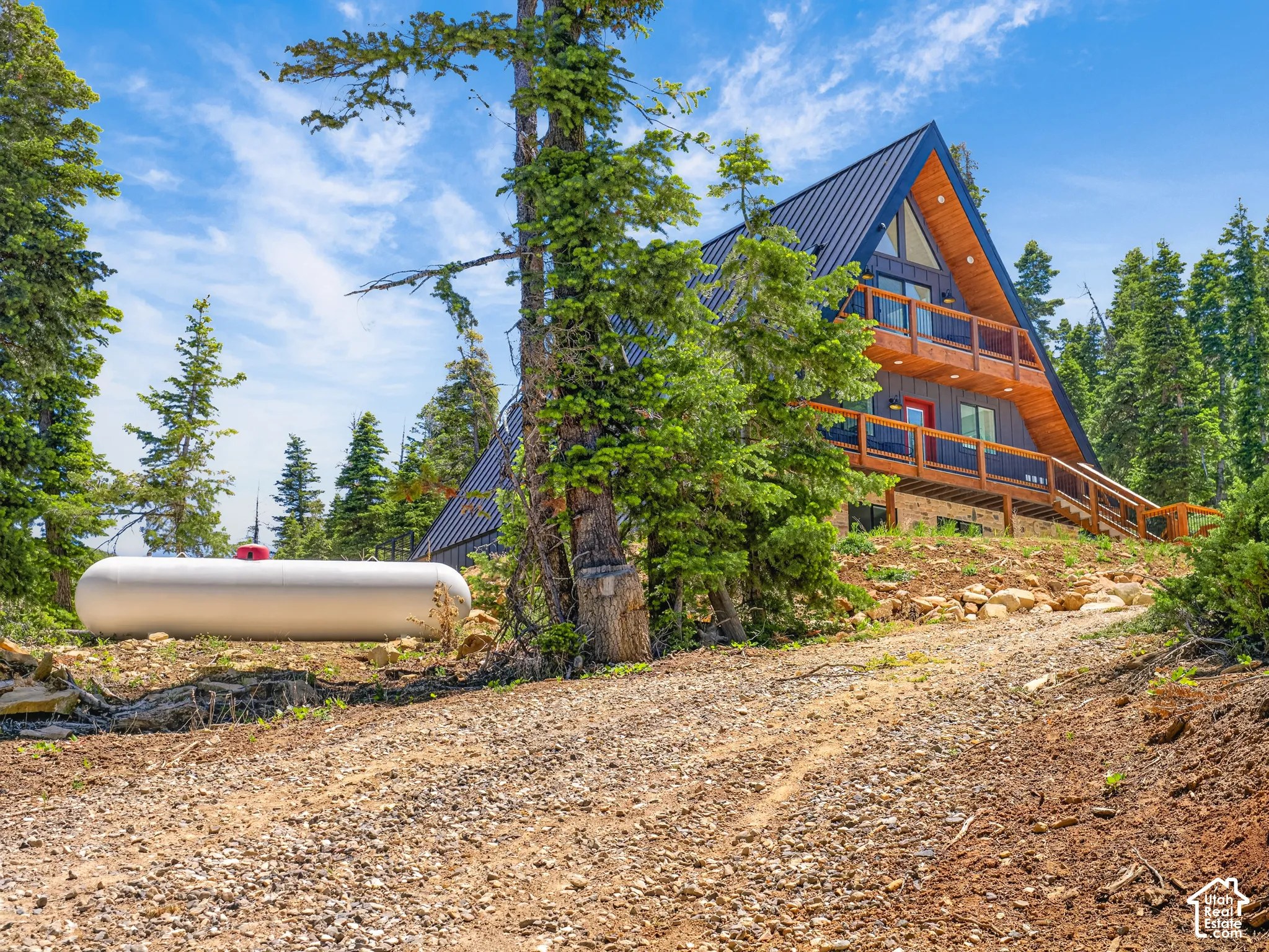 A-frame exterior with dark blue metal roofing, wood siding, multiple balconies, and a red entry door