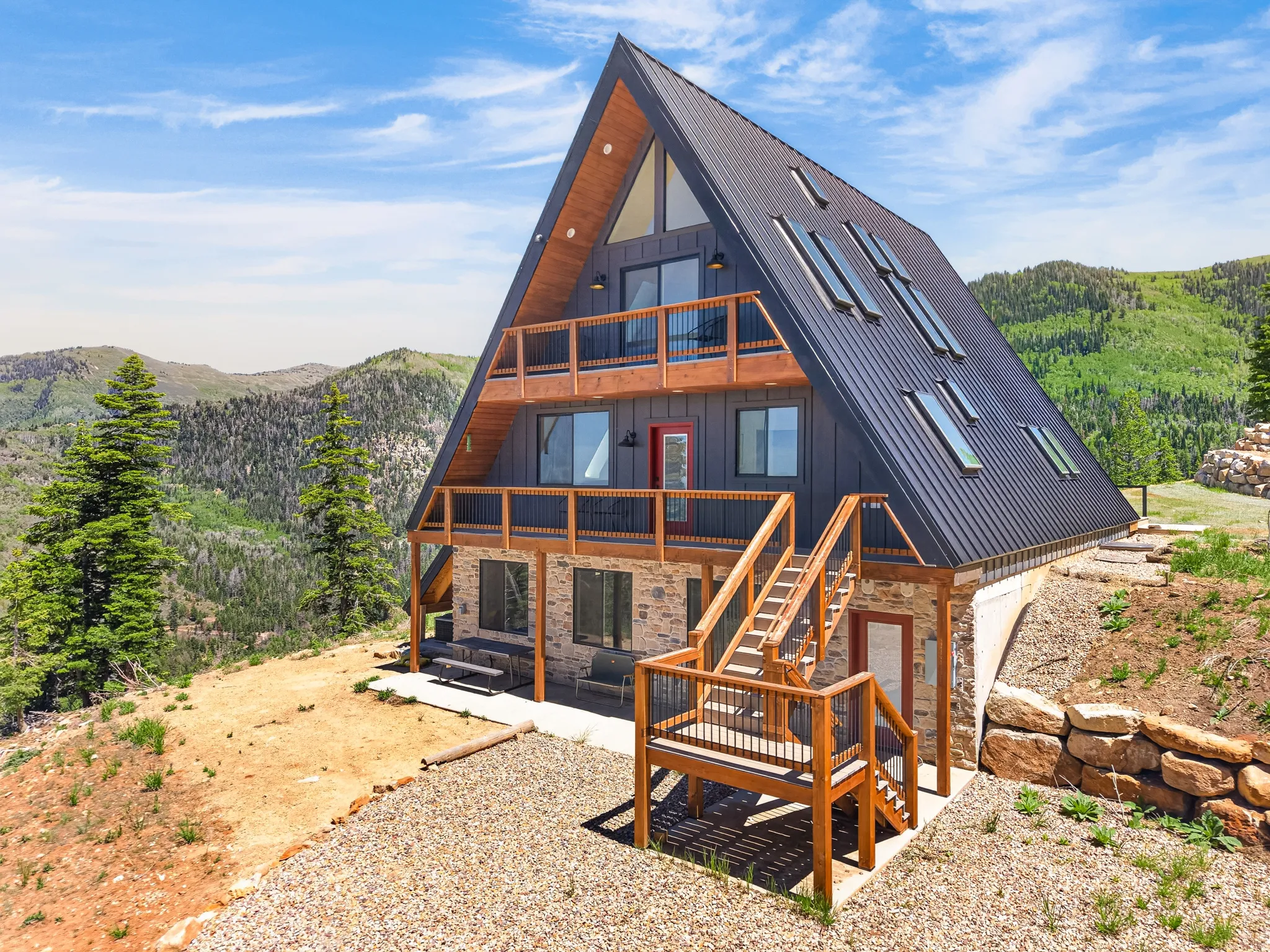 Striking A-frame architecture with a dark metal roof, multiple skylights, and wood-finish trim