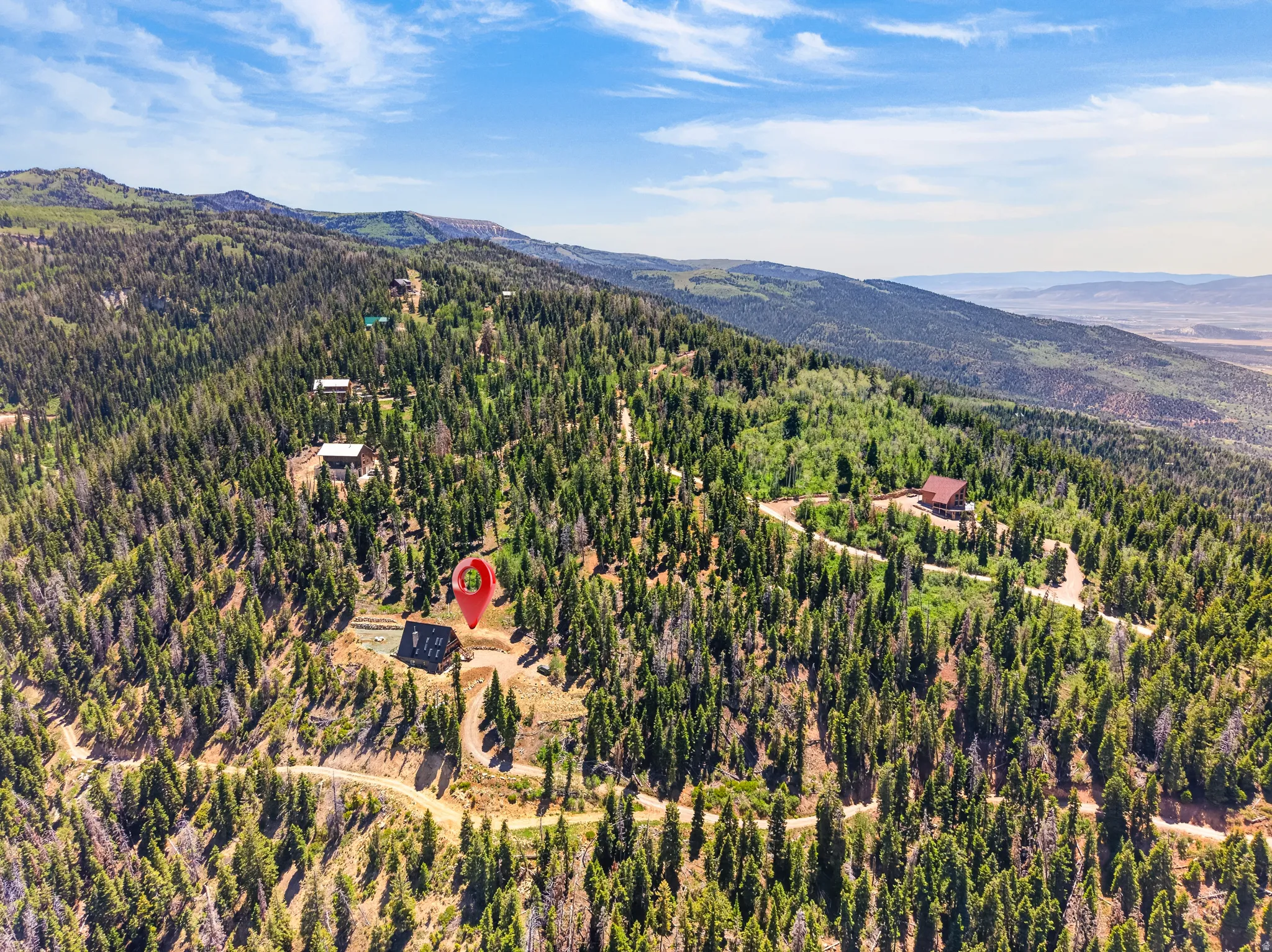 Hillside property featuring a cabin-style structure with a dark roof, surrounded by extensive evergreen forestry