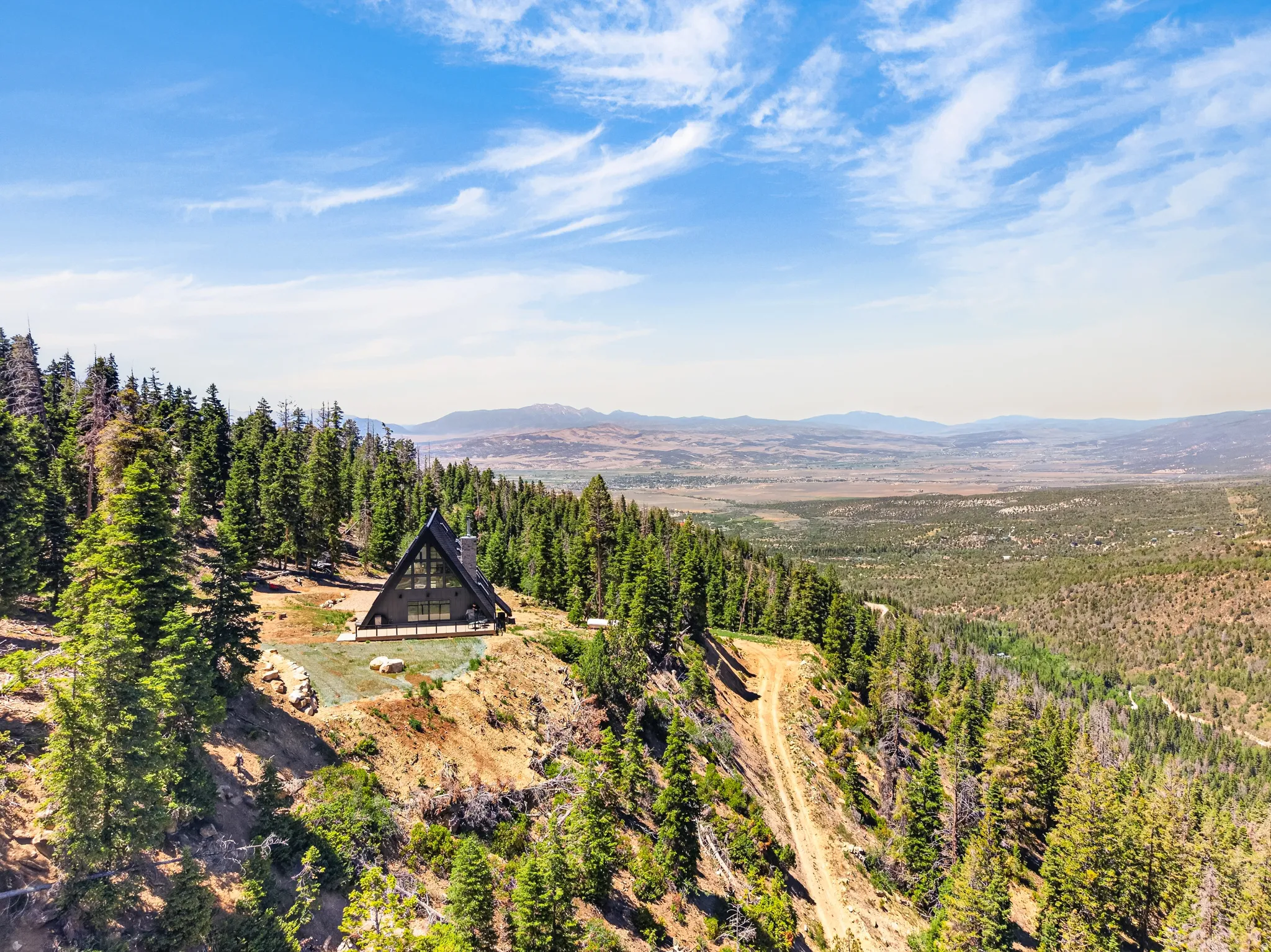 A-frame architectural style with expansive glazing, surrounded by mature evergreen trees