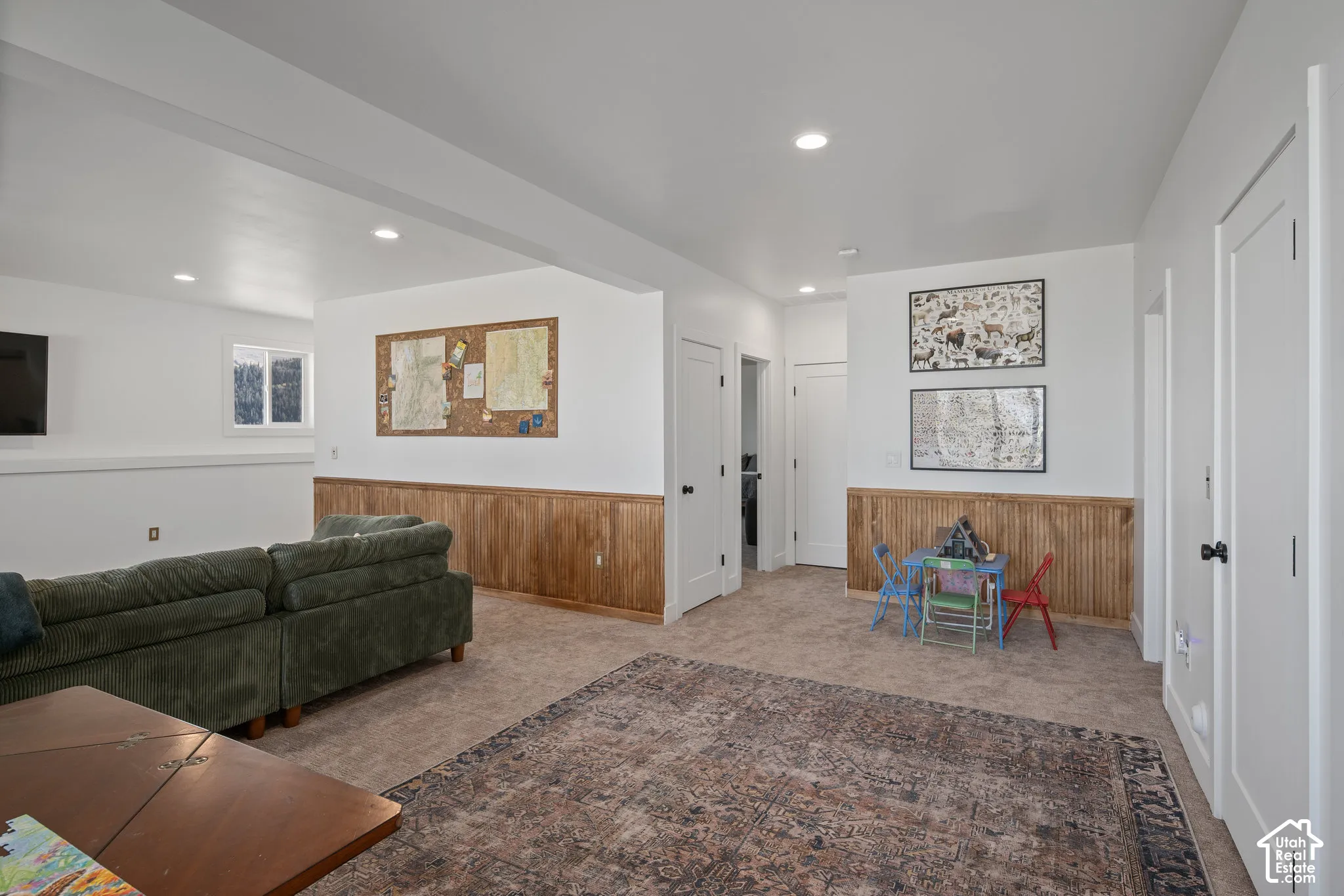Living room featuring wood walls, wainscoting, light colored carpet, and recessed lighting