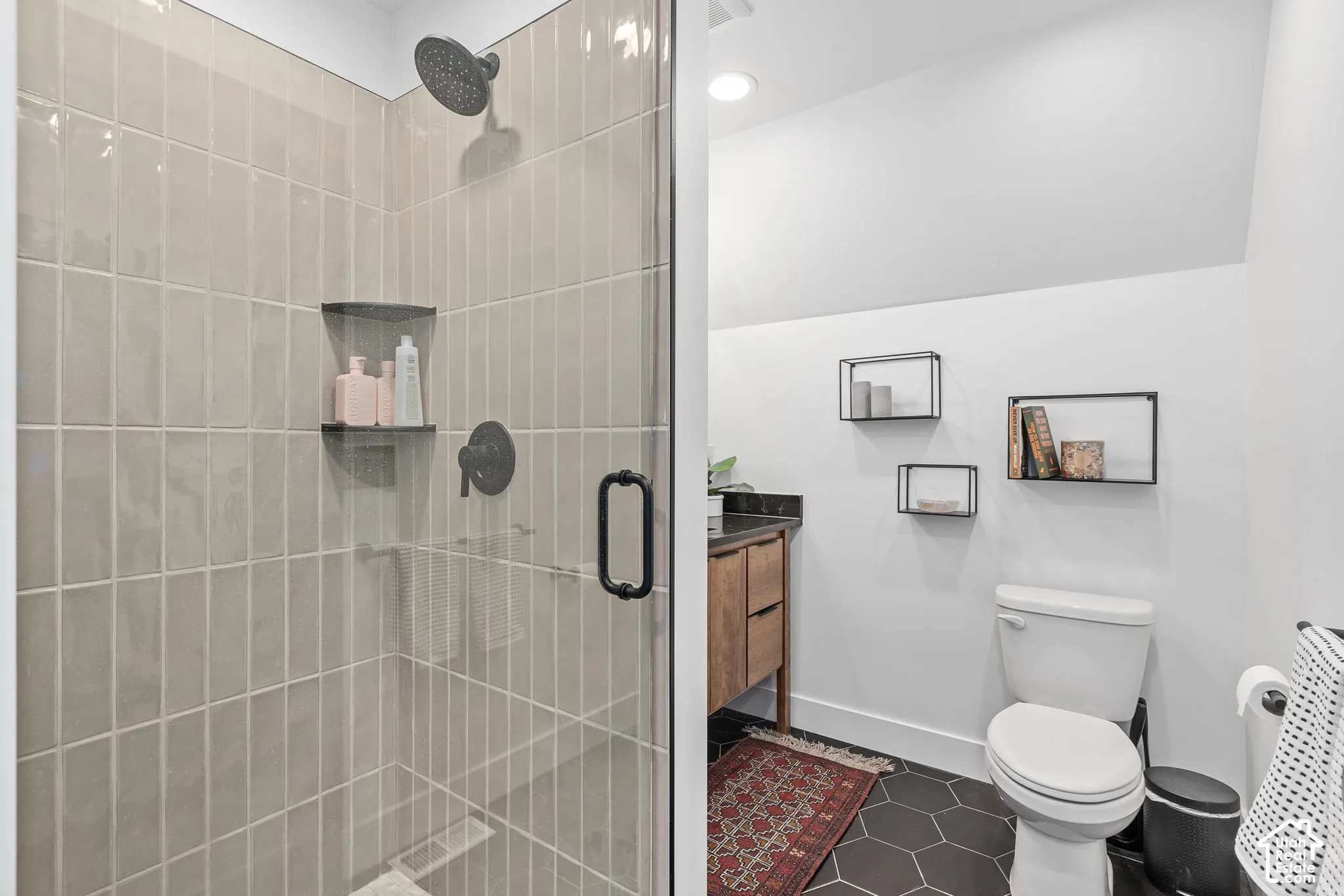 Bathroom with vanity, a stall shower, and dark tile patterned flooring