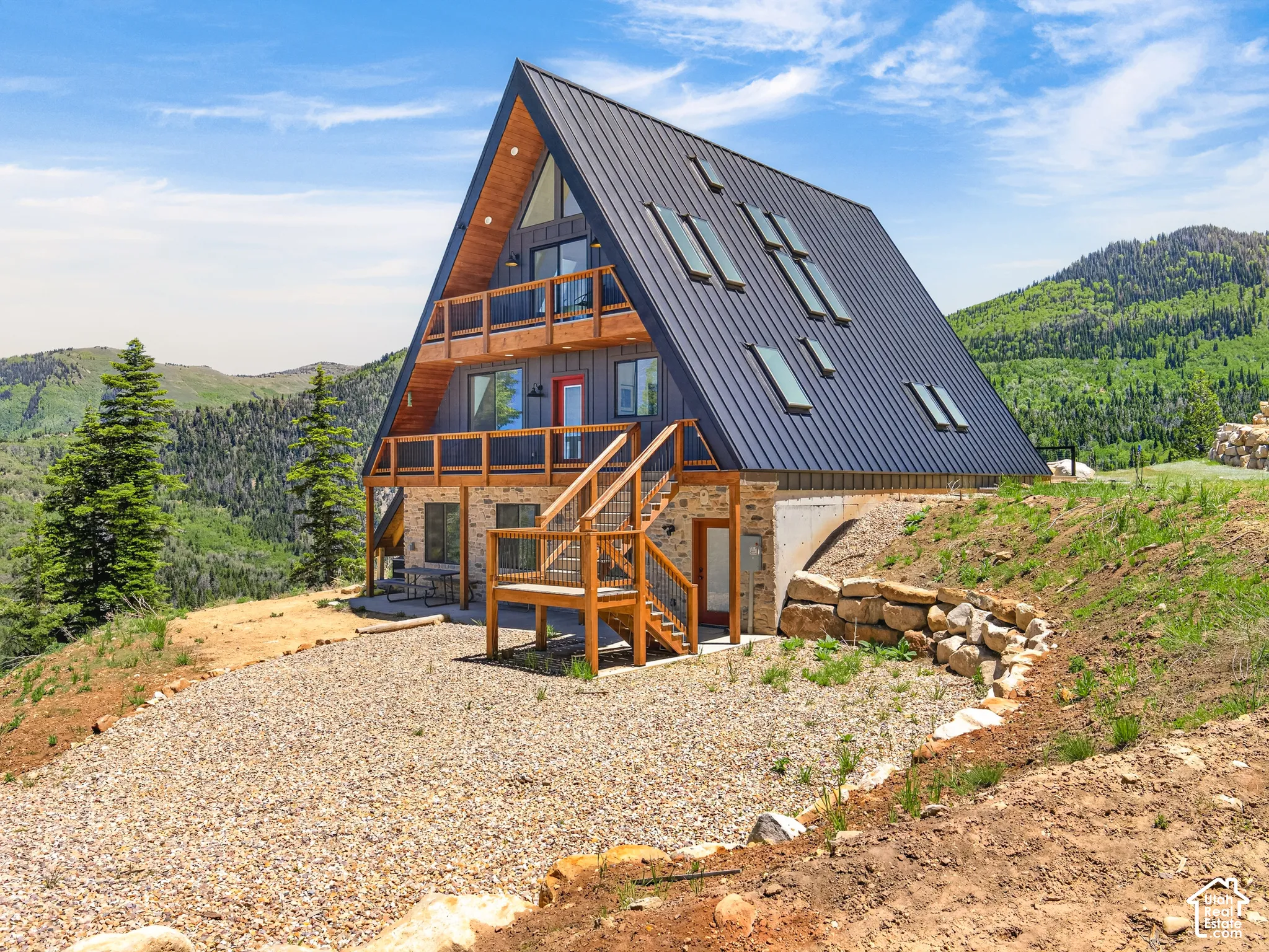 Contemporary A-frame residence featuring a dark metal roof with multiple skylights