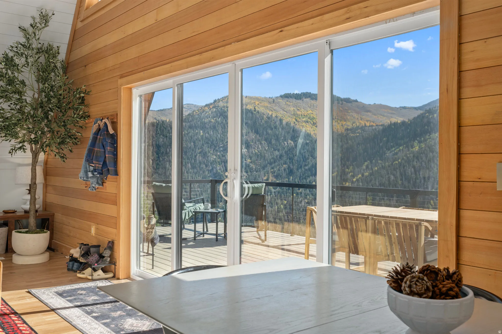 Doorway to outside with wooden walls, a mountain view, a wooded view, and wood finished floors