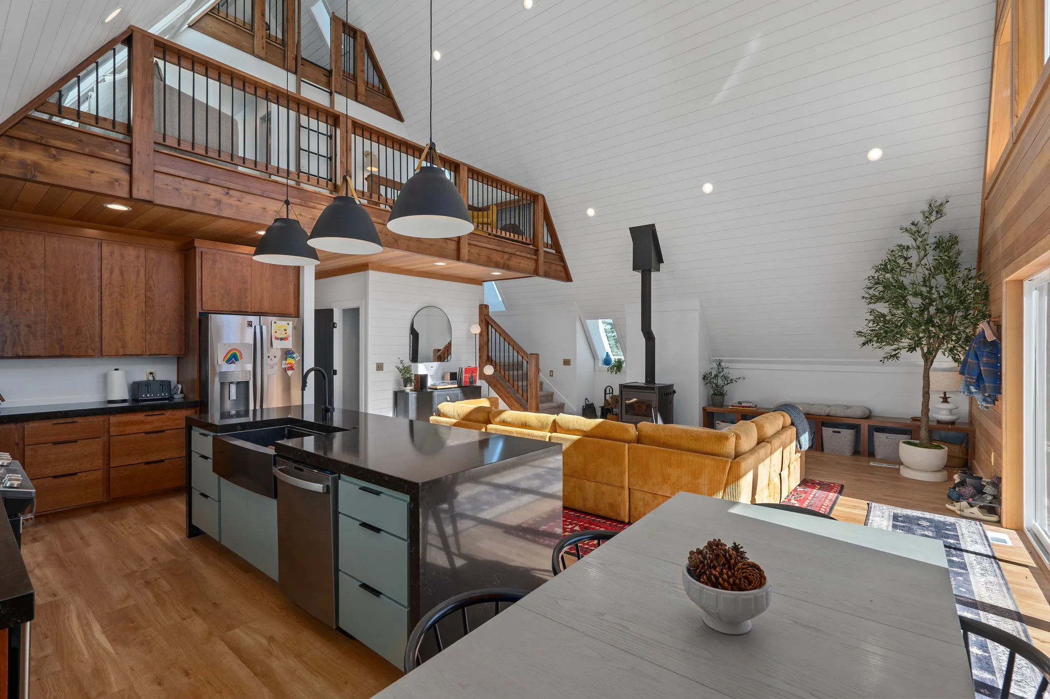 Kitchen with light wood-style flooring, modern cabinets, vaulted ceiling, open floor plan, and stainless steel appliances