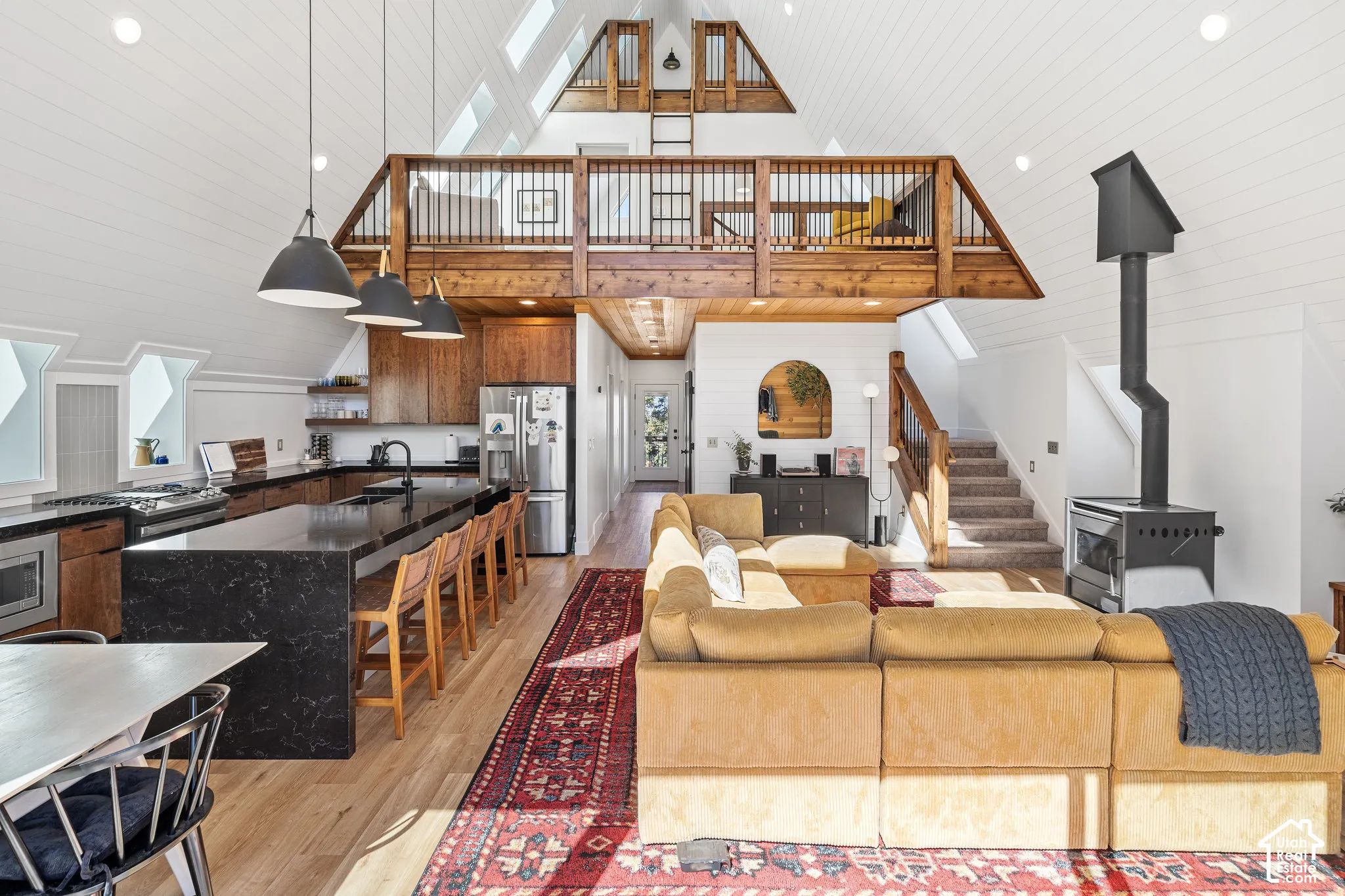 Living room featuring recessed lighting, light wood-style flooring, vaulted ceiling, and a wood stove