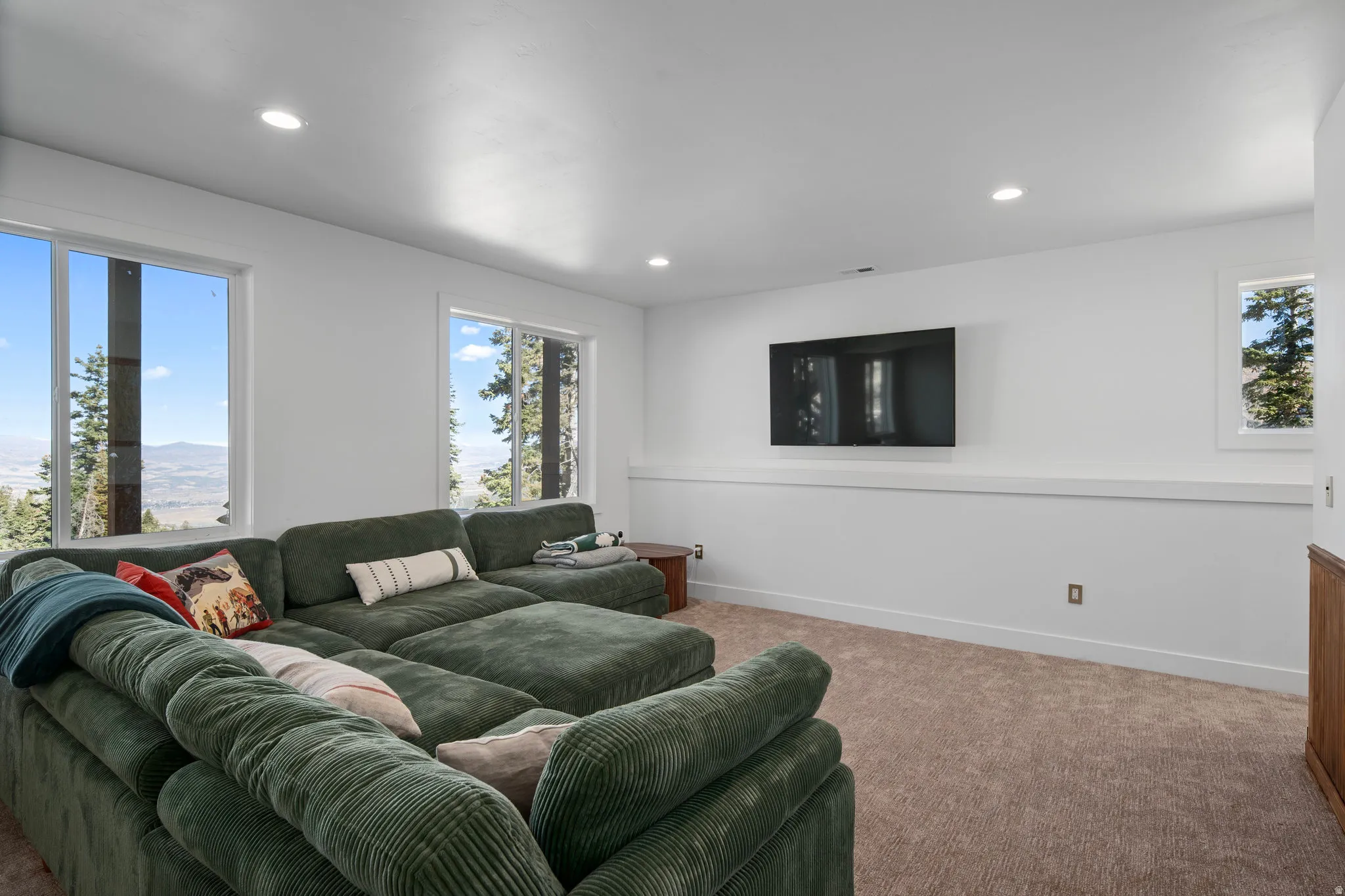 Carpeted living area with recessed lighting and baseboards