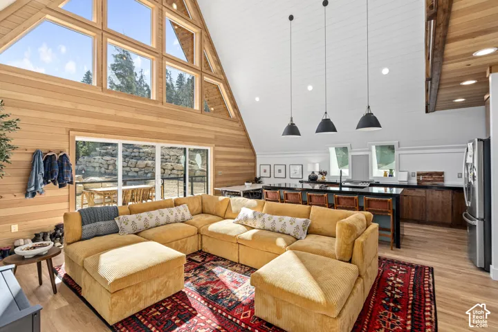 Living area with light wood finished floors, wood walls, recessed lighting, and a high wood ceiling
