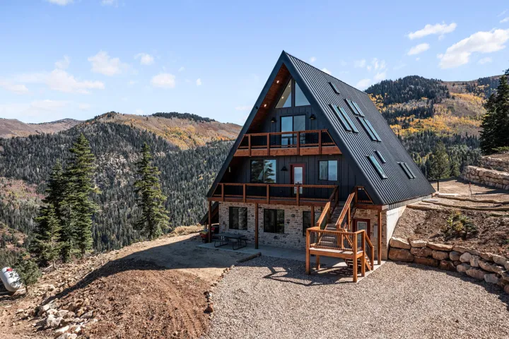 Back of property with a mountain view, a patio area, and stone siding