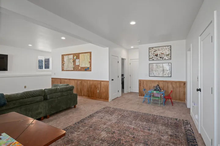 Living room featuring wood walls, wainscoting, light colored carpet, and recessed lighting