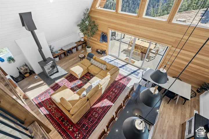 Living area with wood walls, a high ceiling, plenty of natural light, a wood stove, and wood finished floors