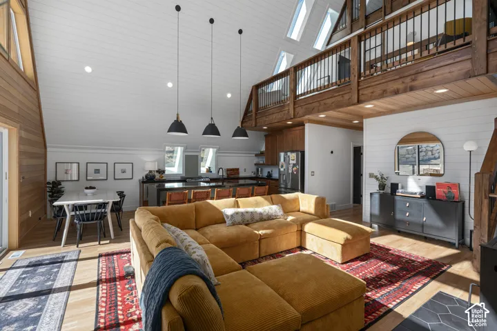 Living room featuring wooden walls, light wood-style flooring, recessed lighting, and a vaulted wood ceiling