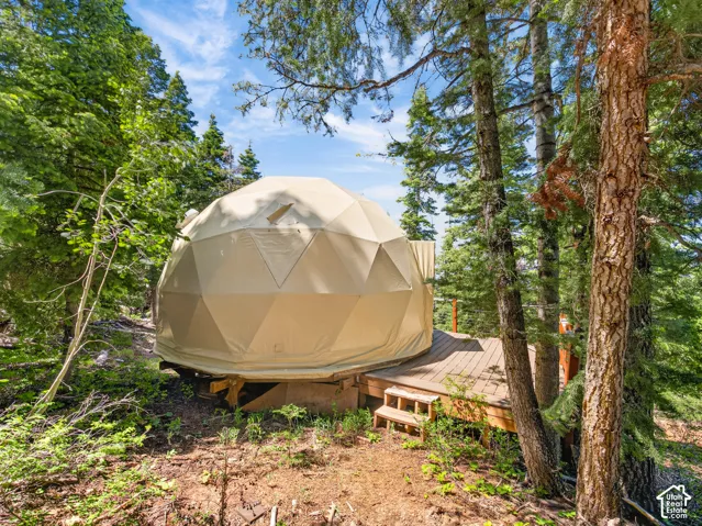 Geodesic dome structure featuring a beige canvas exterior and a private wood deck
