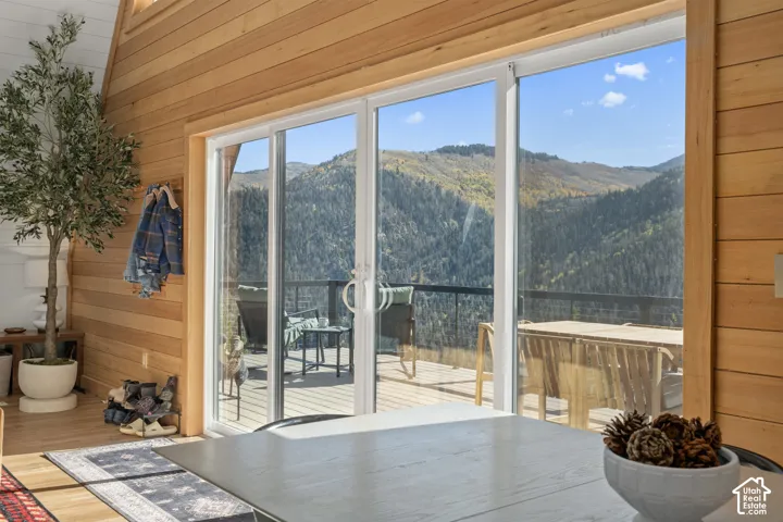 Doorway to outside with wooden walls, a mountain view, a wooded view, and wood finished floors