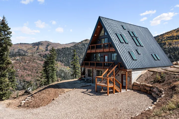 Back of property with a mountain view, stone siding, and a patio