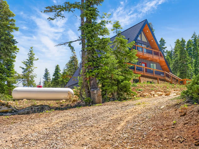 A-frame exterior with dark blue metal roofing, wood siding, multiple balconies, and a red entry door