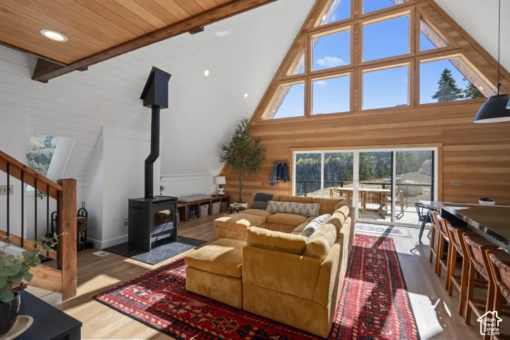 Living area featuring a wood stove, wood finished floors, wood walls, a high wood beamed ceiling, and recessed lighting