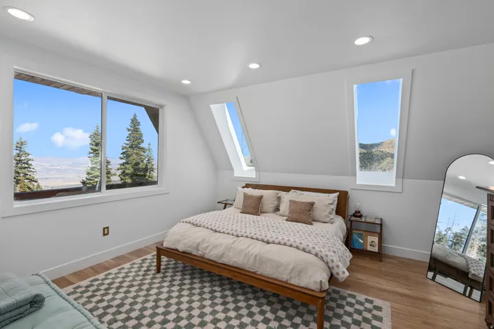 Bedroom with light wood-style floors, multiple windows, and recessed lighting