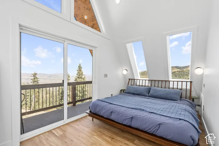 Bedroom featuring light wood-style flooring, a mountain view, access to exterior, and a high ceiling