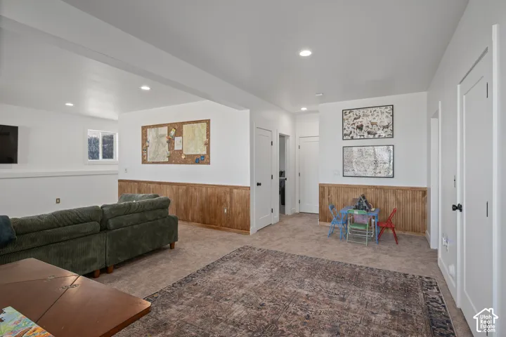 Living room featuring wood walls, wainscoting, light colored carpet, and recessed lighting