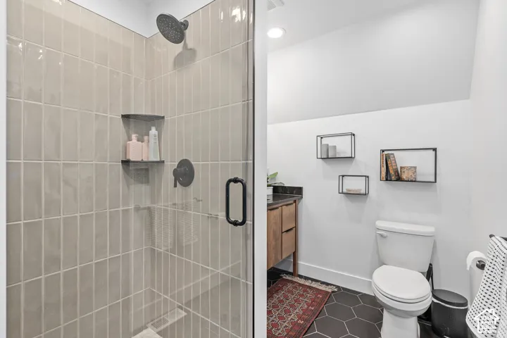 Bathroom with vanity, a stall shower, and dark tile patterned flooring