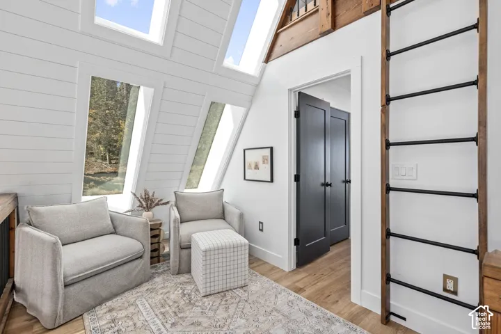 Sitting room featuring light wood-style floors, wood walls, and a high ceiling