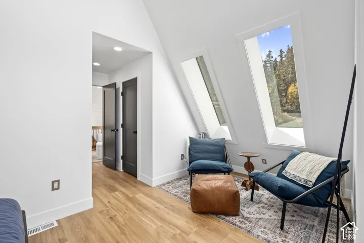 Sitting room featuring light wood-style flooring, recessed lighting, and a high ceiling