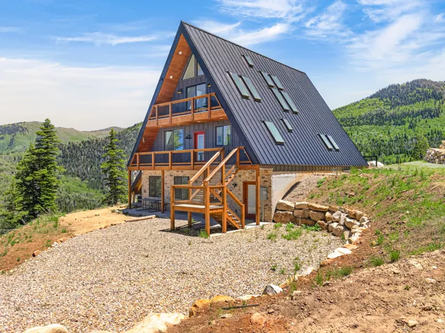 Contemporary A-frame residence featuring a dark metal roof with multiple skylights