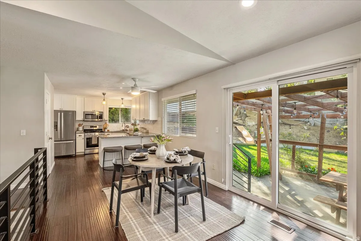Dining area with dark wood finished floors, ceiling fan, and vaulted ceiling