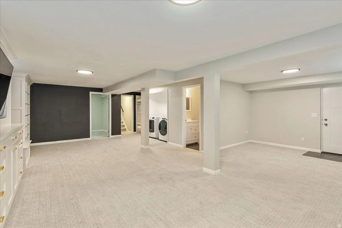Finished below grade area with light carpet, washing machine and clothes dryer, and recessed lighting