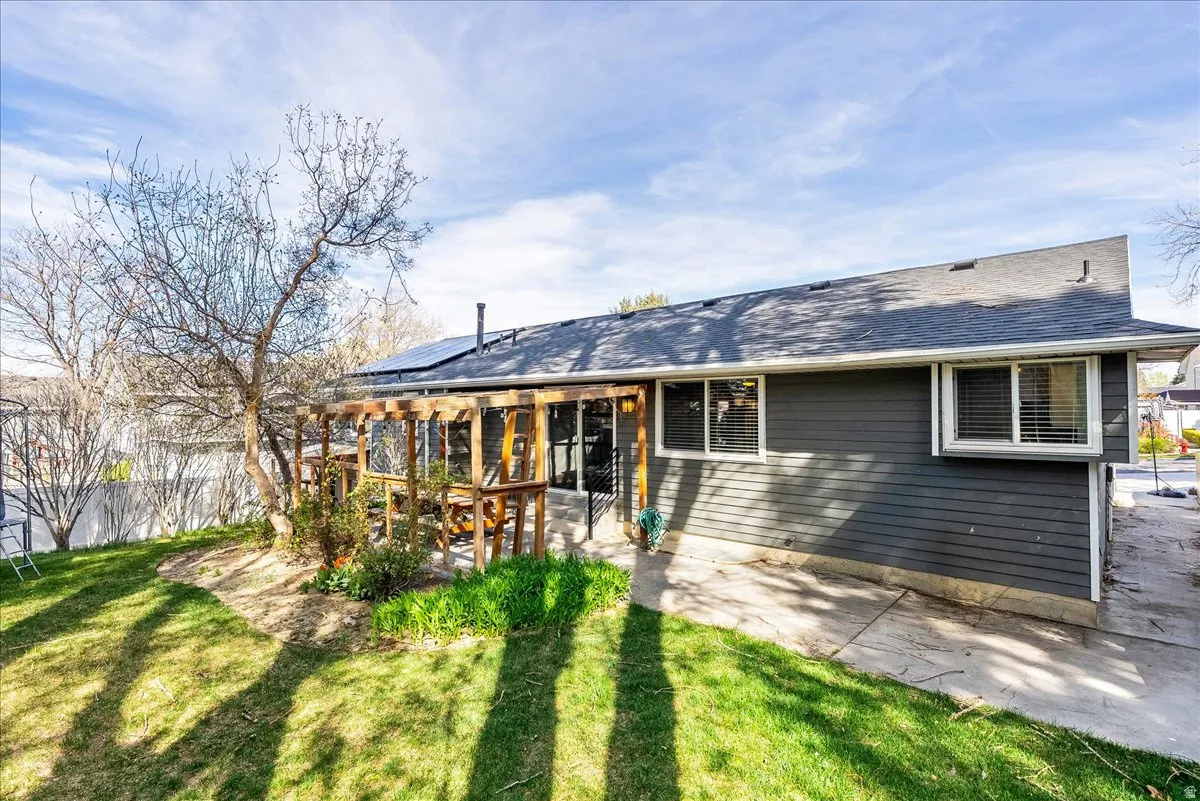 Rear view of house featuring solar panels, a patio area, and a shingled roof