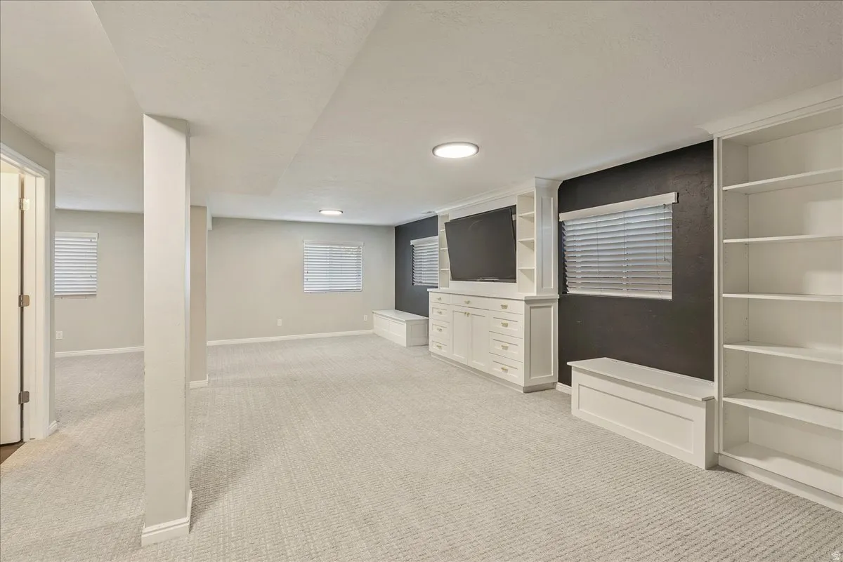 Finished below grade area with light carpet and a textured ceiling