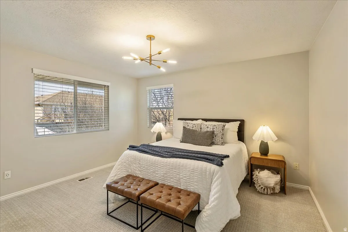 Bedroom featuring light carpet, a textured ceiling, and hanging lights