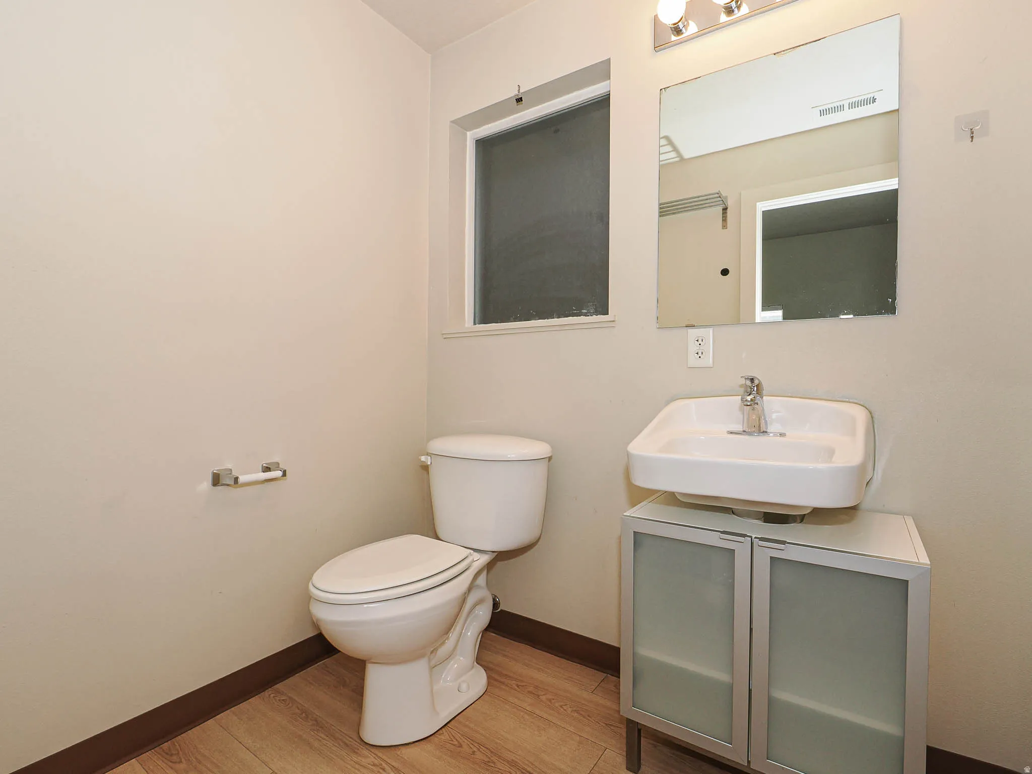 Half bathroom with light wood-style floors and vanity