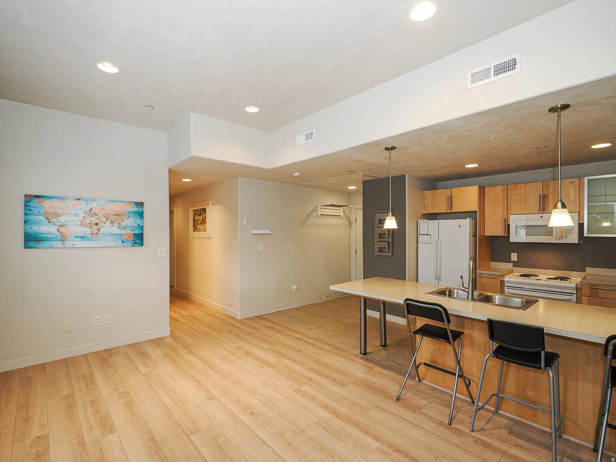 Kitchen featuring a breakfast bar, white appliances, light countertops, and light wood-type flooring