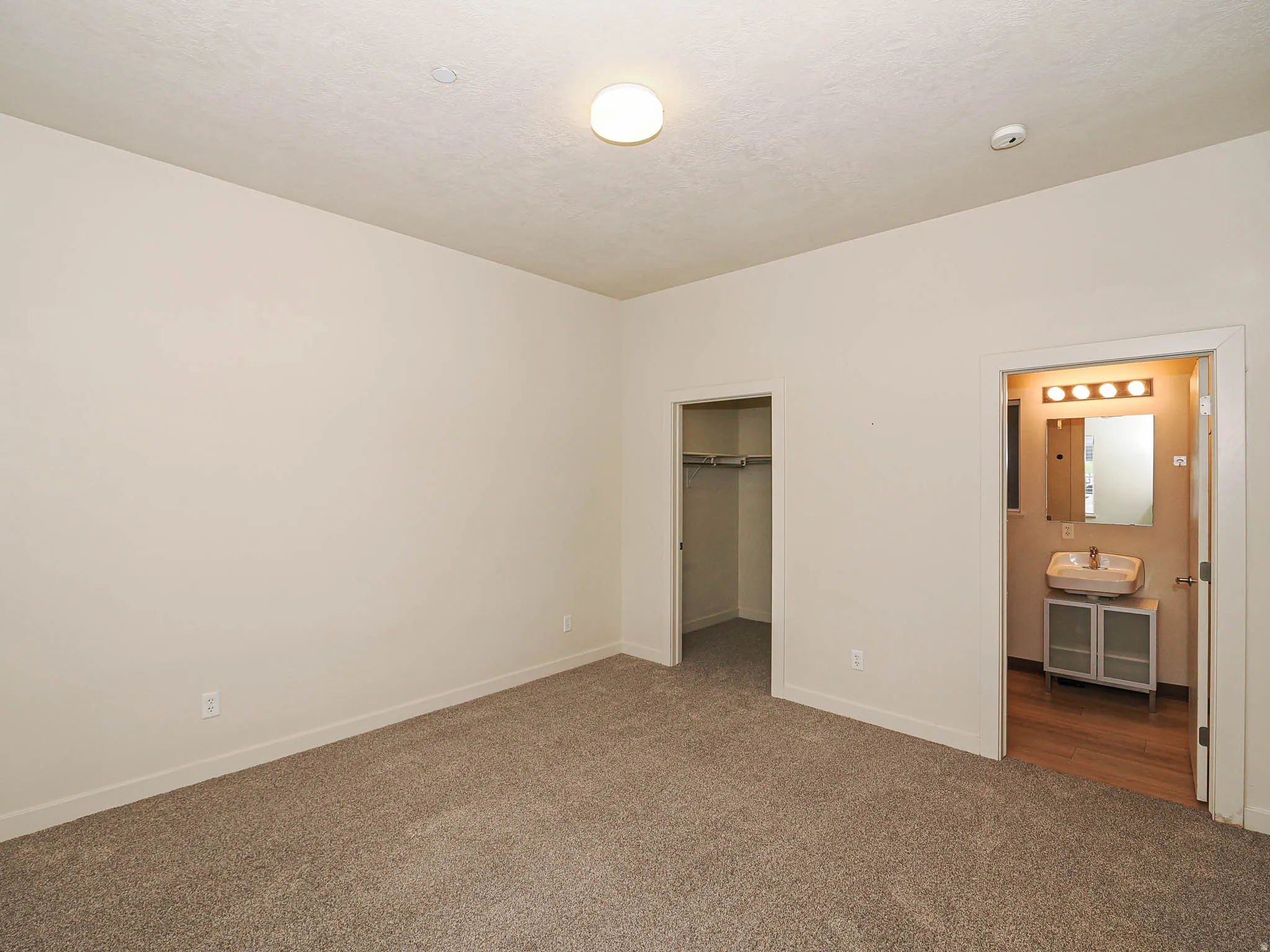 Unfurnished bedroom featuring a walk in closet, dark colored carpet, and connected bathroom