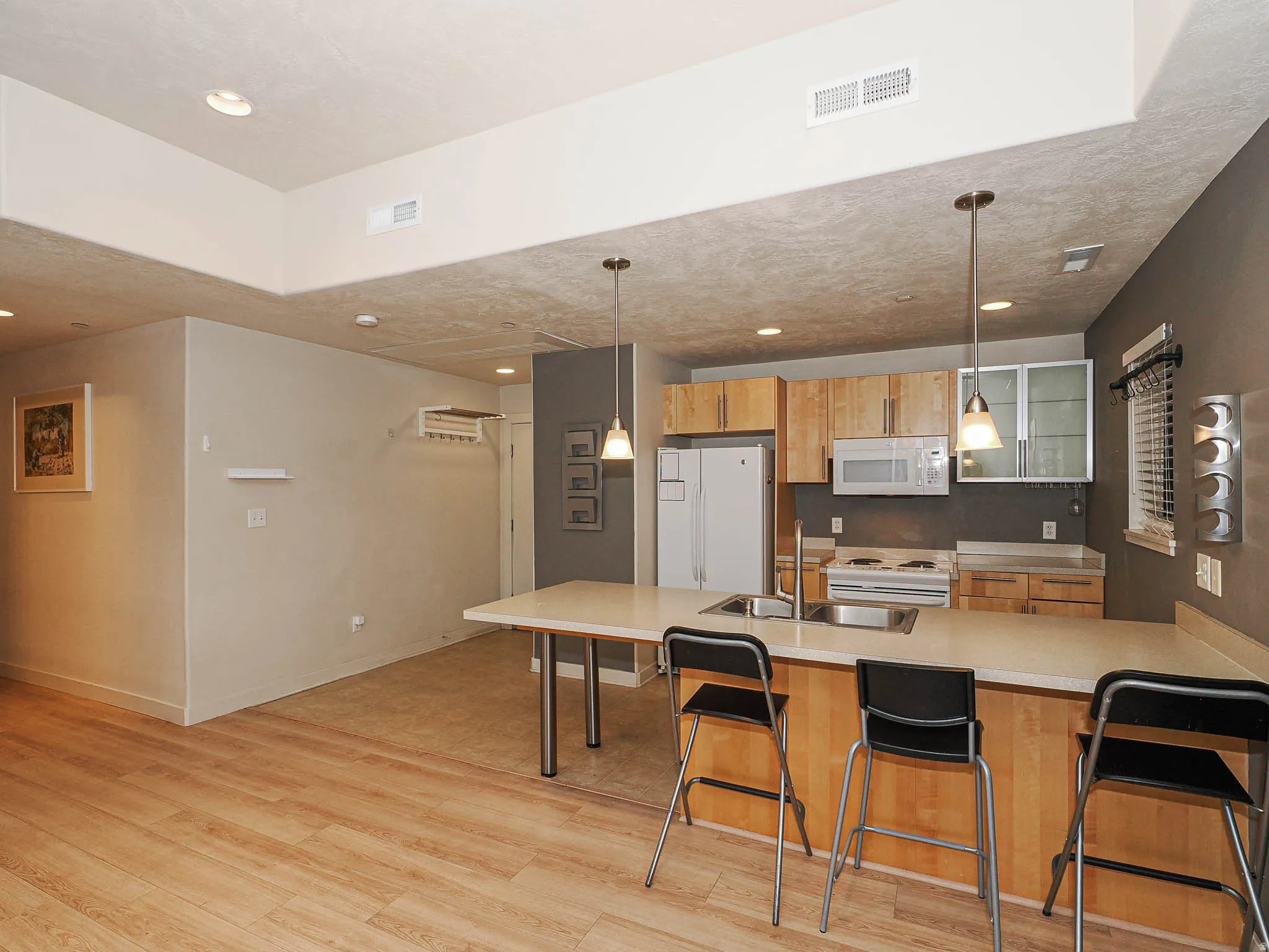 Kitchen with a peninsula, a breakfast bar area, hanging light fixtures, and light wood-style floors