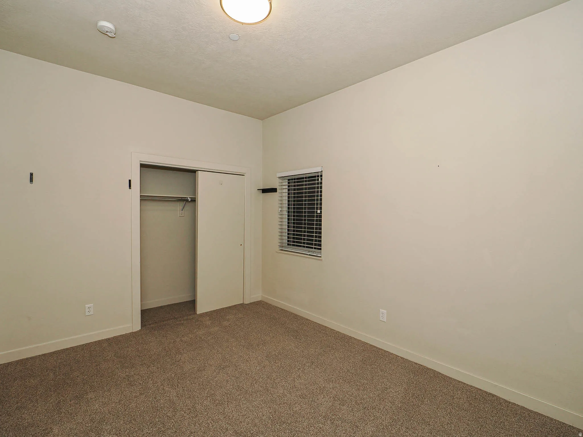 Unfurnished bedroom with dark colored carpet and a closet