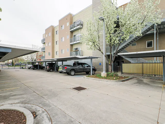 View of apartment building / complex featuring covered parking