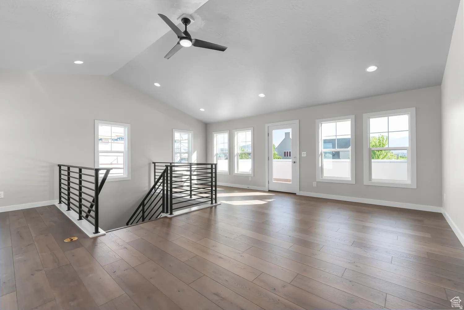 Empty room with ceiling fan, healthy amount of natural light, lofted ceiling, dark wood finished floors, and recessed lighting