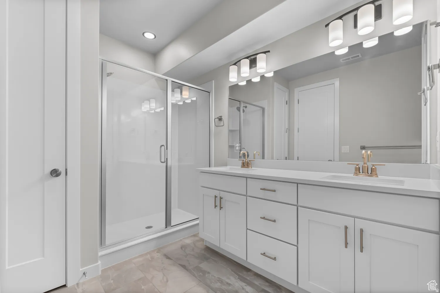 Full bath with double vanity, a stall shower, light marble finish floors, and recessed lighting
