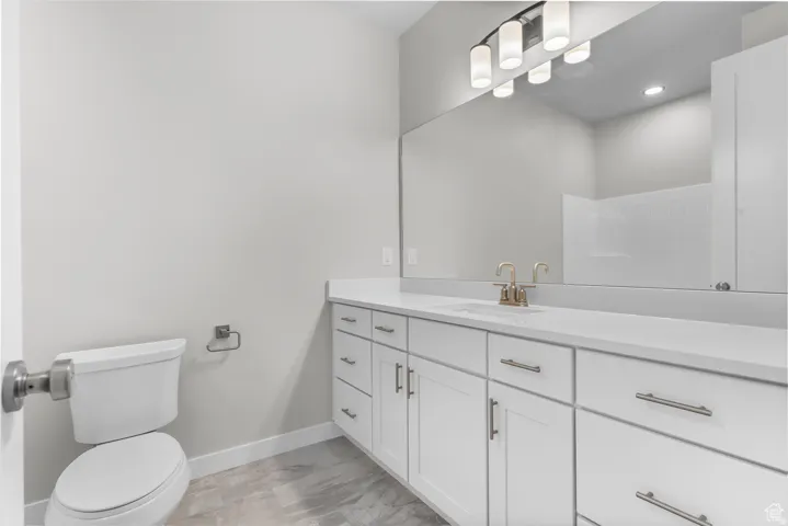 Bathroom featuring vanity, light marble finish floors, and recessed lighting