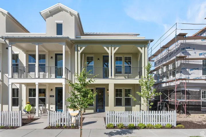 View of front of property with a standing seam roof, stucco siding, a fenced front yard, and covered porch