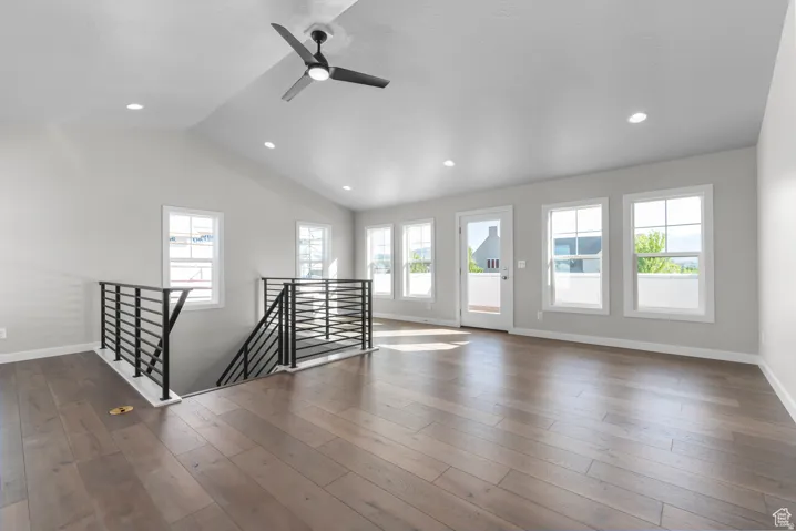 Empty room with ceiling fan, healthy amount of natural light, lofted ceiling, dark wood finished floors, and recessed lighting