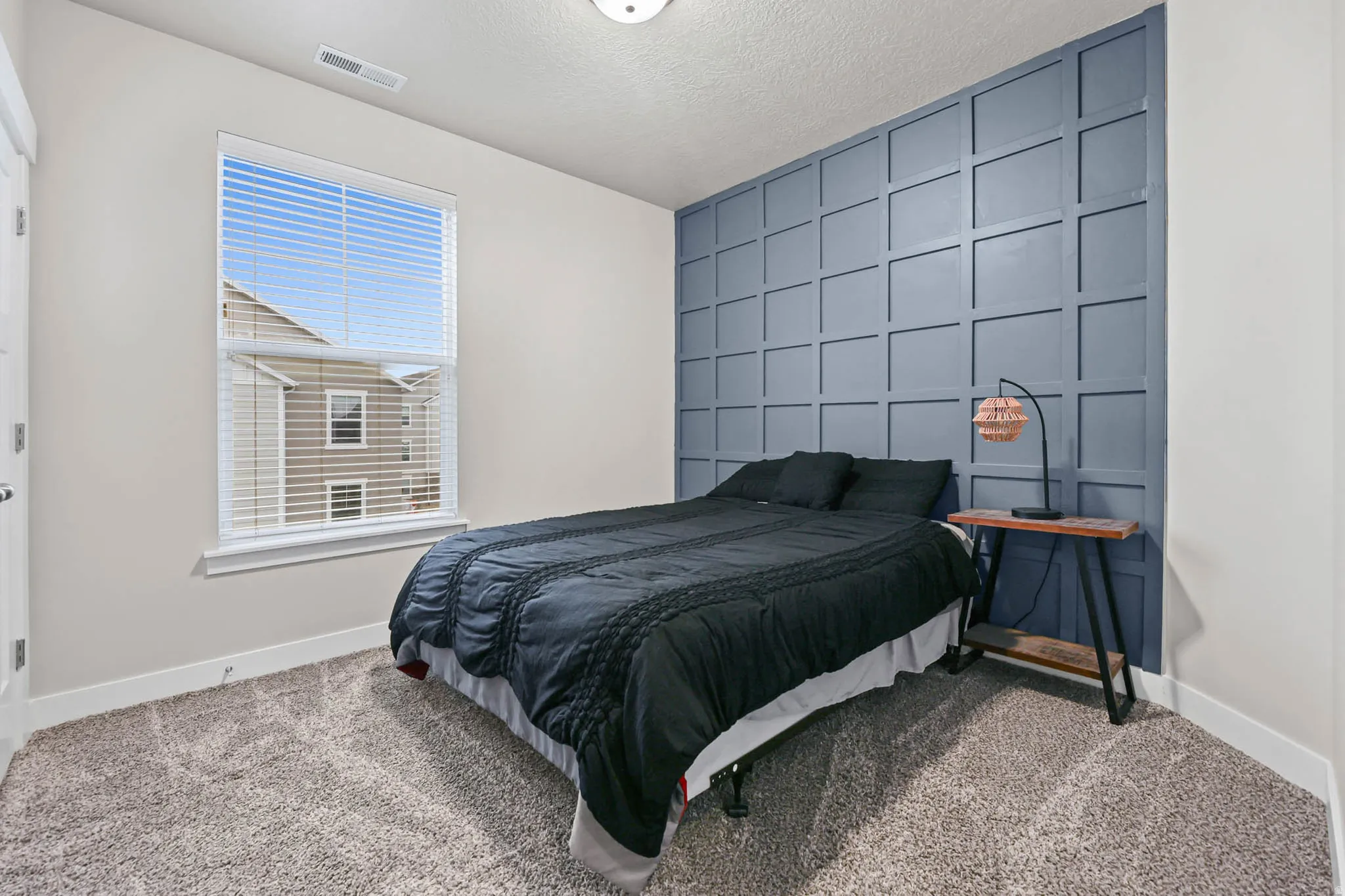 Carpeted bedroom featuring an accent wall, a decorative wall, and a textured ceiling