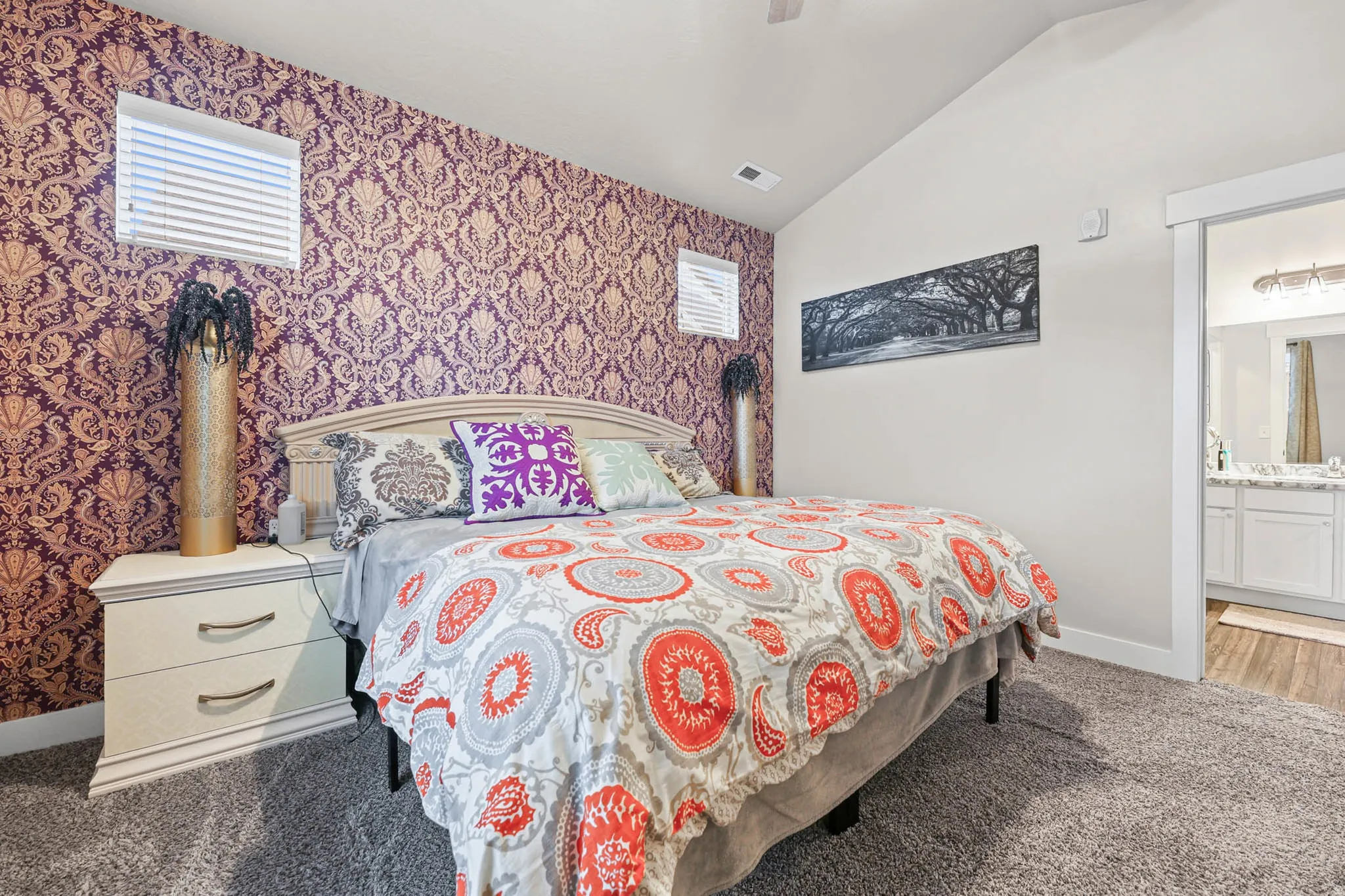 Carpeted bedroom featuring lofted ceiling, ceiling fan, wallpapered walls, and ensuite bathroom