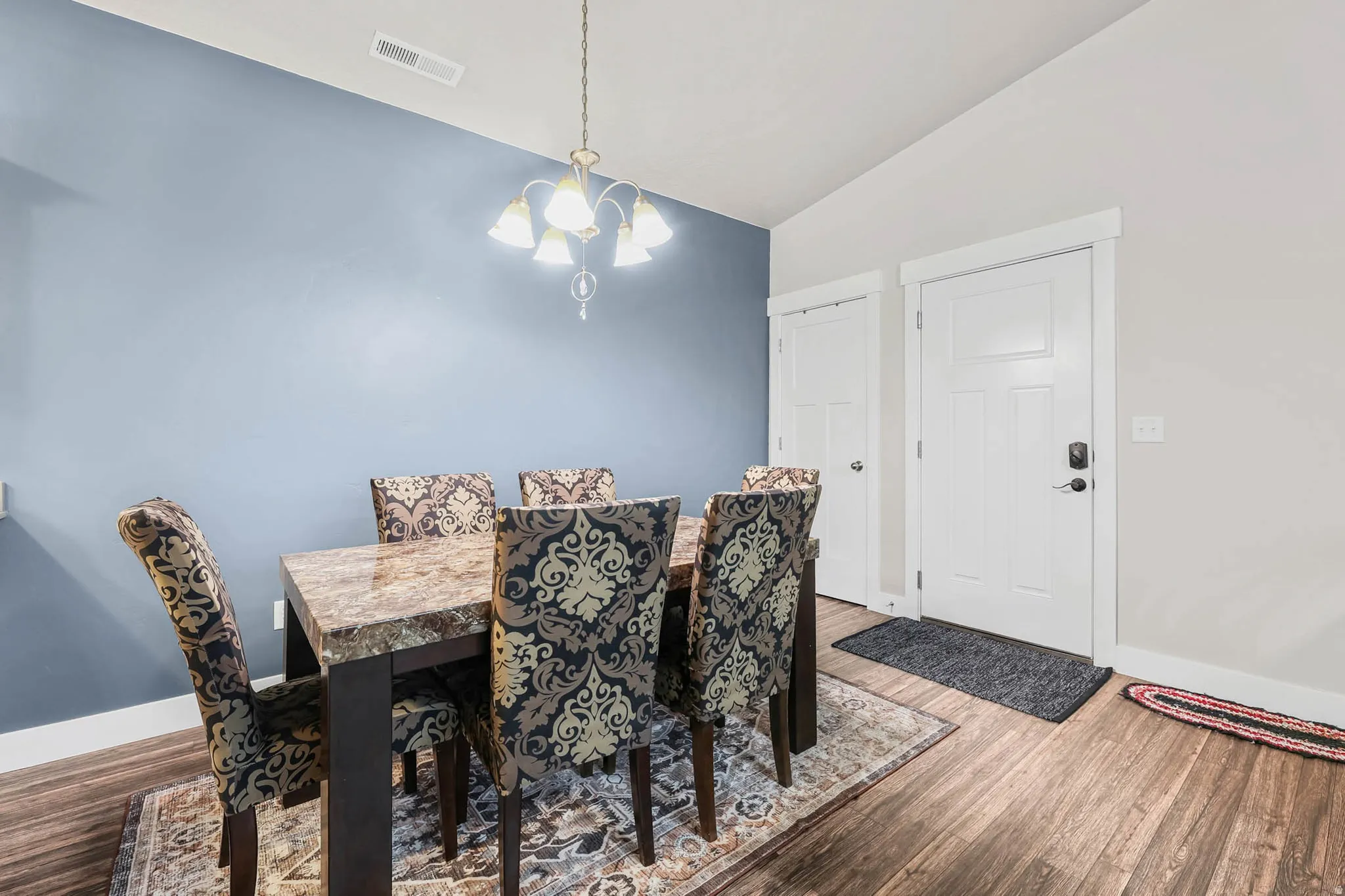 Dining space with hanging lights, lofted ceiling, and wood finished floors
