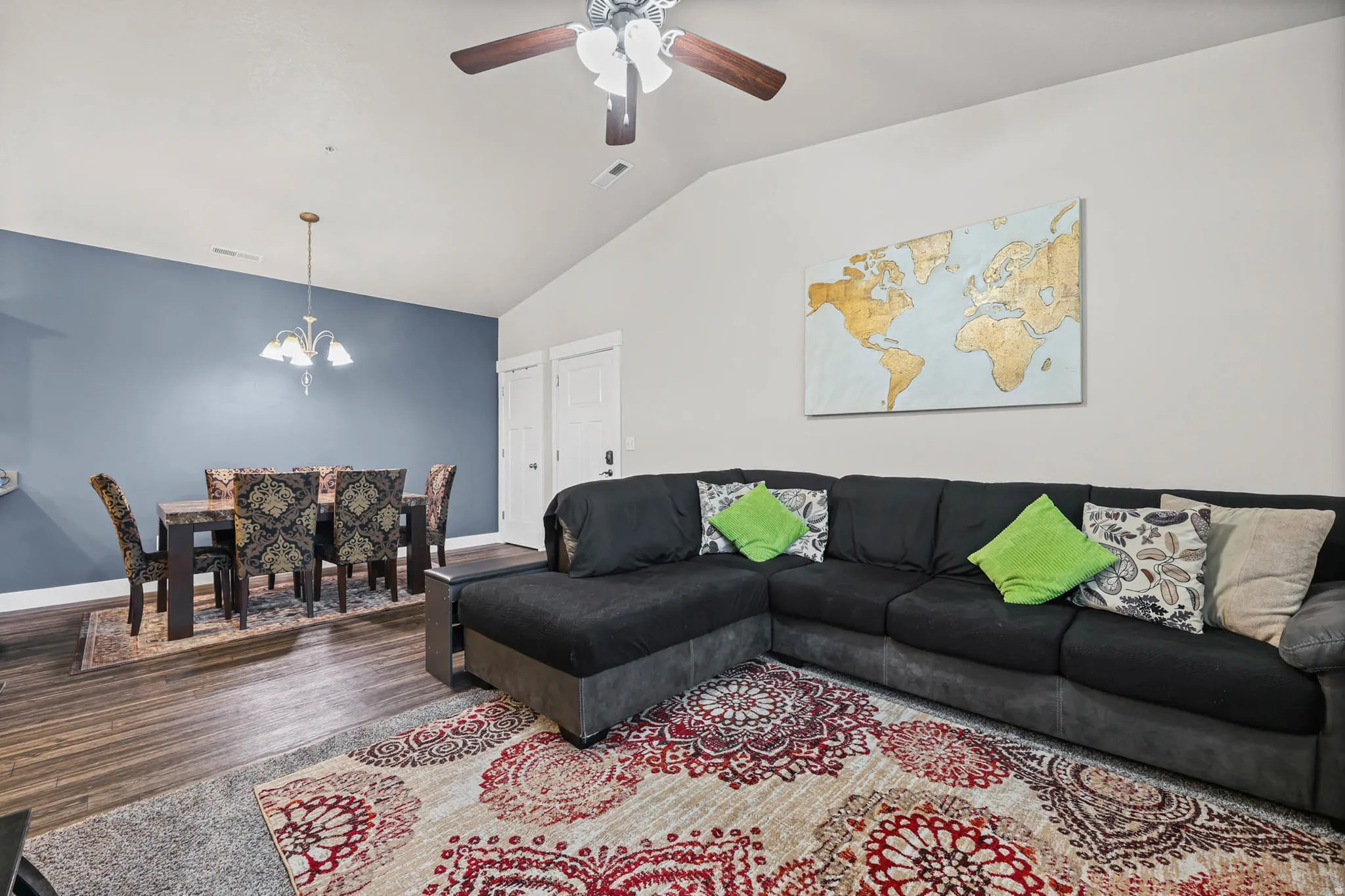 Living room featuring vaulted ceiling, a ceiling fan, wood finished floors, and suspended lighting