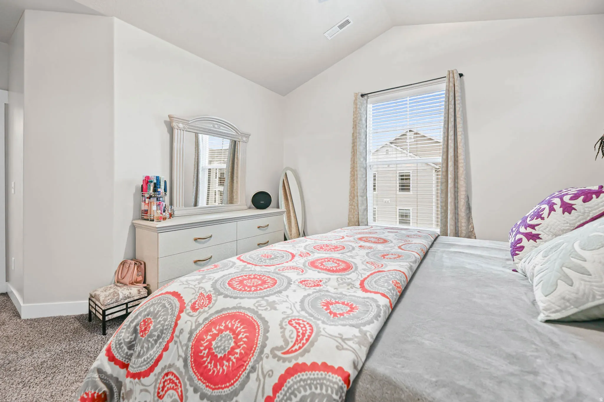 Bedroom with lofted ceiling, multiple windows, and light colored carpet